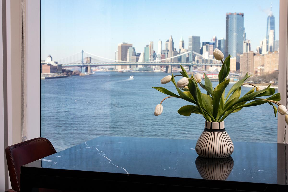 Dining Table Detail with Flowers in Vase in Front of Large Window with Waterfront and City Views