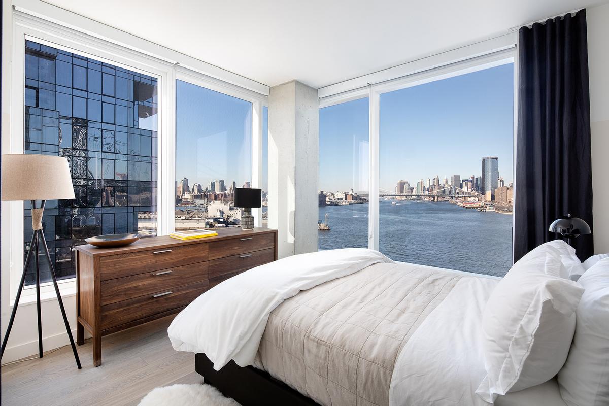 Modern Bedroom Wood Dresser, Modern Lamp, Wood Floor and Oversized Windows with Waterfront and City Views